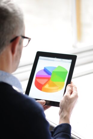 man looking at a tablet with a pie chart displayed