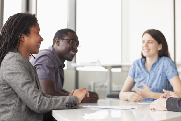 Two women and a man smiling in a team meeting