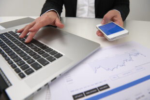 Close-up of hands using laptop and mobile phone