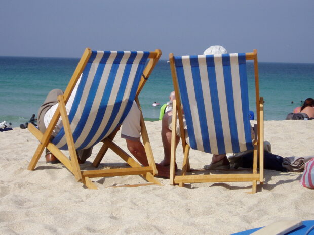 Two people sitting in deckchairs at the seaside