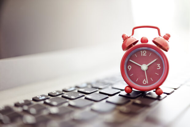 Red alarm clock on computer keyboard