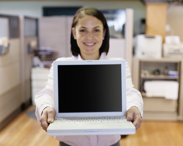 Businesswoman holding laptop, smiling towards the camera