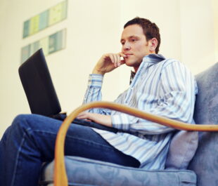 man sitting down looking at a laptop