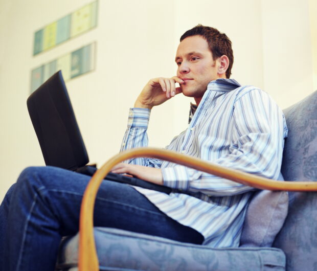 Man sat on chair looking at laptop