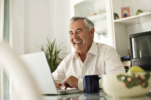 man, smiling using a laptop