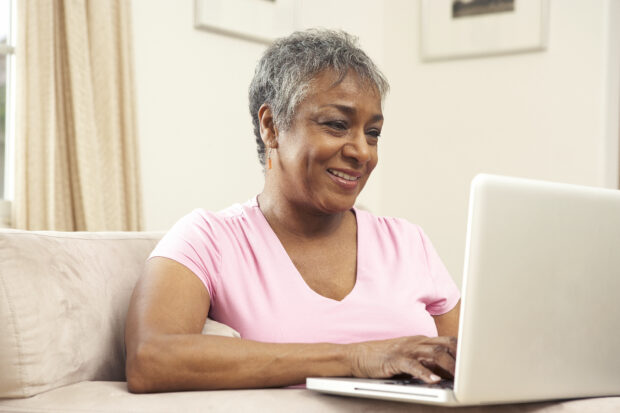 A smiling woman sitting down, looking at a laptop