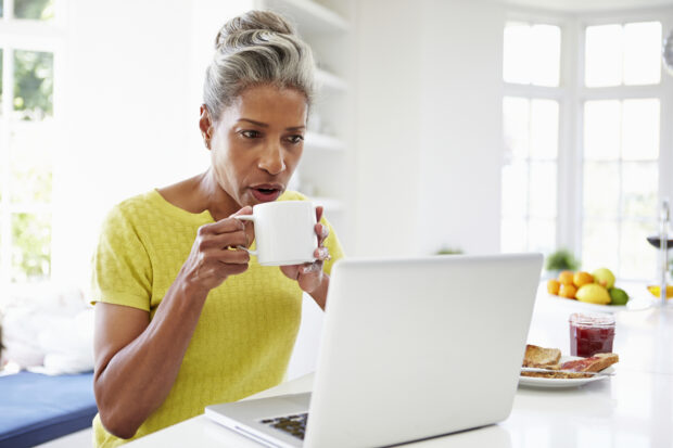 woman having breakfast looking at laptop