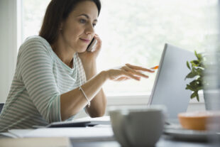 Business woman, at a desk using laptop and phone