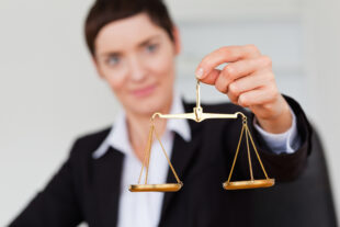 Businesswoman holding a miniature replica of the scales of justice