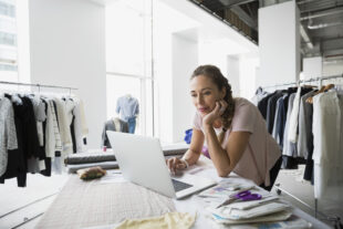 Woman clothes designer looking at a laptop in her studio