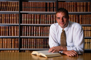 smiling man, looking at a book in an office library