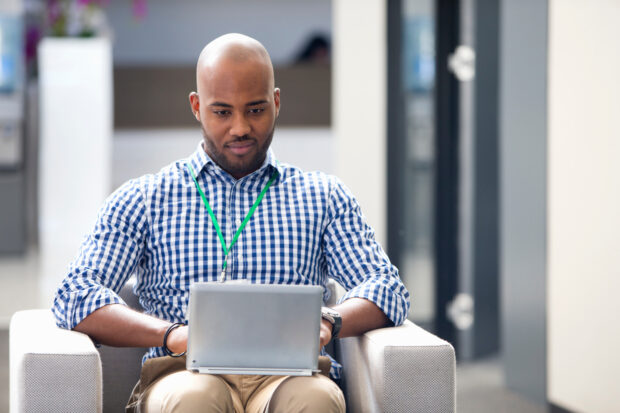 man sitting down looking at his laptop