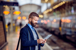 business man at train station reading tablet