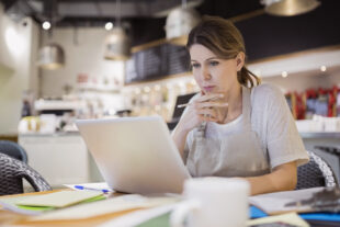 Serious business owner working at laptop in cafe