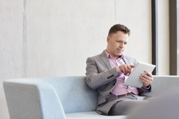 Businessman using a digital device, sitting on a sofa